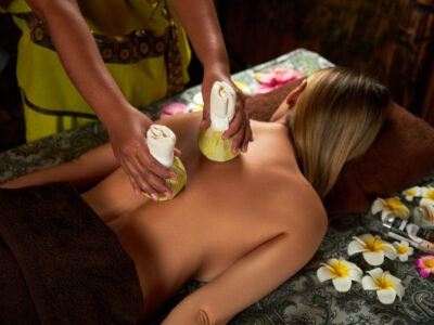Asian woman does back massage with herbal bags to lady patient in oriental spa salon close view. Alternative medicine and aromatherapy for relax