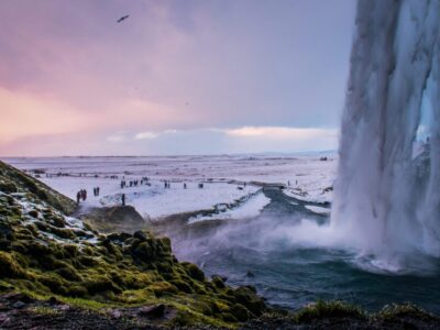 scenic-view-waterfall-by-snow-covered-landscape-against-cloudy-sky-sunset