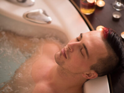 young handsome man enjoys relaxing in the jacuzzi with candles and champagne at luxury resort spa