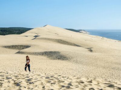 woman-walking-sandy-beach-against-clear-blue-sky