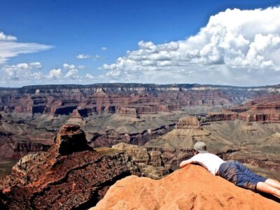 man-lying-rock-formation-grand-canyon-against-sky