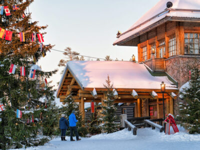 Couple at Santa Claus Office in Santa Village with Christmas trees, Lapland, Finland, on Arctic Circle in winter.