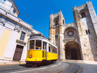 Lisbon city old town and famous yellow tram 28 in front of Santa Maria cathedral on a sunny summer day. Trams in Lisbon, Portugal. Tourist attraction. High quality photo