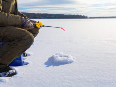 Man in winter clothes  fishing on ice. Concept of winter fishing with copy space.