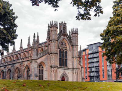St Andrews Cathedral in Glasgow, a historic Gothic Revival church surrounded by green space and modern city buildings under a cloudy sky.